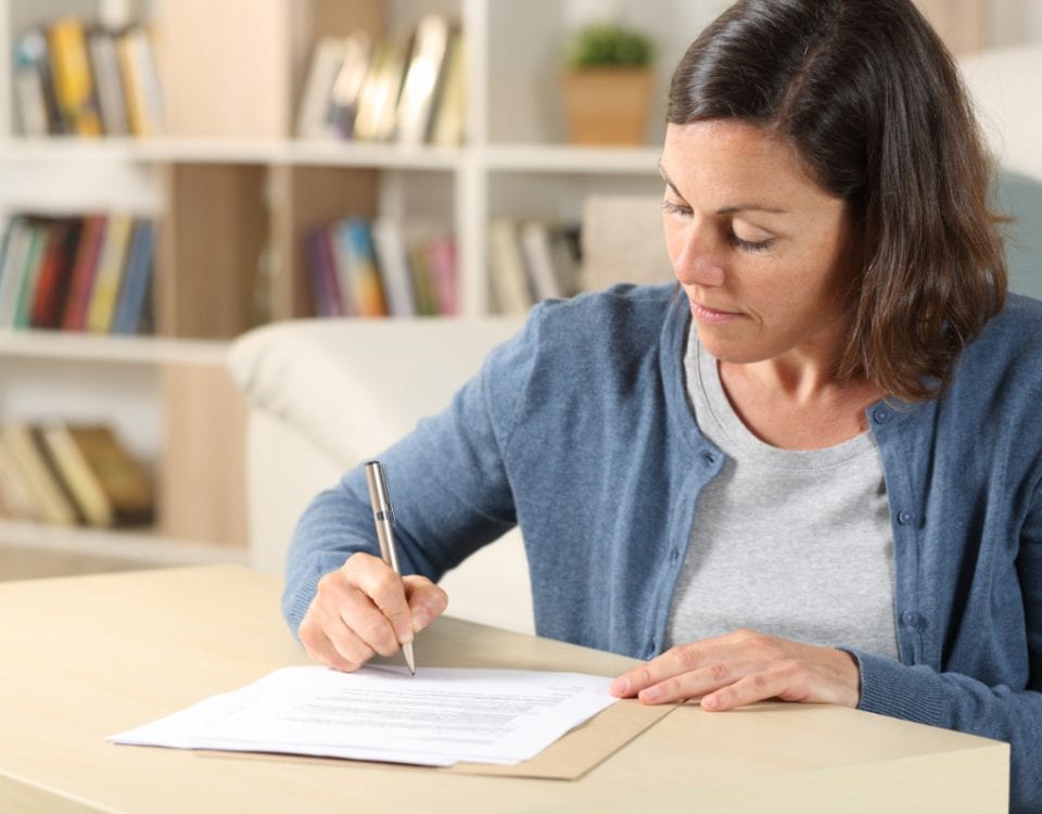Serious adult woman signing a document